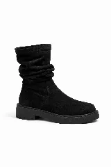 Bota bucanera de caña alta en material simil gamuza color negro, con suela track plana y punta redondeada.