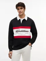 Chomba de rugby de manga larga Tommy Hilfiger en colaboración con Cadillac Formula 1 Team. Presenta un diseño en bloques de color negro, blanco y rojo, con cuello estilo rugby en color blanco y cierre frontal oculto. Incluye el logo de Cadillac en fuente script y el logo de Tommy Hilfiger estampados en el pecho.