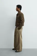 Cazadora cropped fit de efecto piel en color verde militar, con cuello solapa, manga larga con puño abotonado, bolsillos frontales de plastrón con solapa y cierre de botonadura.