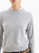 Sweater de tejido de punto color naranja, con cuello redondo, mangas largas y puños acanalados. Presenta una textura suave y un diseño clásico de calce estructurado.