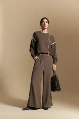 Sweater de punto color marrón con diseño de líneas blancas en contraste. Presenta cuello redondo, mangas largas y puños tejidos, con una estética minimalista y moderna.