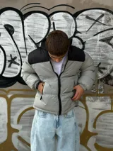 Campera puffer gris con sección superior negra y cierre frontal.