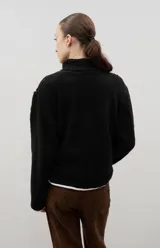 Campera de sherpa color beige con cuello alto, cierre frontal completo y bordado a contra tono en el pecho.