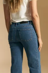 Jean de corte recto y tiro medio, confeccionado en denim elastizado de color negro. Presenta un diseño clásico con cierre de botón y cremallera, bolsillos laterales y traseros, y ruedo con terminación deshilachada.