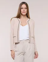 Cardigan corto beige de punto, con silueta entallada, manga larga y cuello redondo. Presenta un ribete decorativo con cadena dorada y detalles azul oscuro en la abertura frontal, el cuello y los bolsillos simulados.