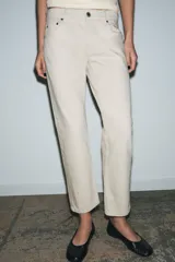 Jeans de tiro medio con corte slim leg, confeccionados en denim color beige. Presentan cintura con trabillas, diseño clásico de cinco bolsillos y cierre frontal con cremallera y botón metálico.