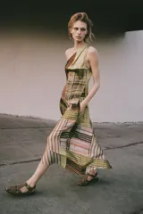 Falda midi de tiro alto con bajo asimétrico y cierre lateral con cremallera oculta. Presenta un diseño de paneles con diferentes estampados geométricos, de rayas y cuadros en tonos verdes, marrones y naranjas.
