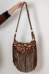 Bandolera de cuero con pelo estampado tipo animal print de ciervo, con flecos largos de gamuza en la parte inferior y correa ajustable.