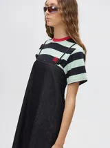 Vestido midi de denim color marrón, con corte holgado, breteles finos con lazos ajustables y detalle de volado en el ruedo.