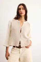 Saco de algodón tejido, color beige con mangas y detalles en blanco, escote en V y cierre frontal de botones.