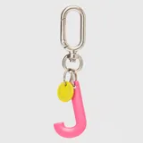 Llavero con dije en forma de letra A color rosado y pequeño dije circular amarillo con logo de la marca grabado. Incluye gancho metálico tipo mosquetón.