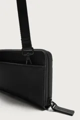 Bandolera rectangular de acabado engomado con cierre de cremallera en el compartimento principal y bolsillo interior con cierre. Incluye asa de hombro ajustable y extraíble.