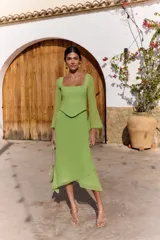 Vestido midi verde claro con efecto dos piezas, compuesto por un corset con escote cuadrado y costuras frontales estructuradas, y falda midi fluida de corte asimétrico. Cuenta con mangas largas semitransparentes.