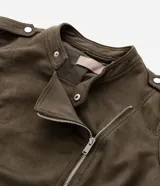 Campera estilo biker confeccionada en gamuza sintética color verde militar. Presenta cierre frontal asimétrico con cremallera metálica, cuello con solapas y botones a presión, y bolsillos laterales con cierre. Incluye detalles de charreteras en los hombros.
