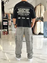 Remera gris oscuro con corte boxy fit de manga corta y cuello redondo. Cuenta con un diseño gráfico frontal con la palabra "CONCEPT" en grandes letras blancas delineadas y líneas decorativas horizontales y en las sisas.