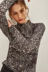 Polera de manga larga con cuello alto, confeccionada en tejido de algodón con estampado floral tipo liberty en tonos oscuros.