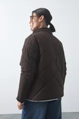 Campera acolchada de nylon color negro, con cuello alto, cierre frontal y botones a presión. Presenta un diseño de rombos y forro interior suave.