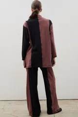 Pantalón de corte recto y tiro alto, confeccionado en algodón con diseño bicolor que combina paneles laterales en negro y panel central en beige, unidos por costuras visibles a contratono.