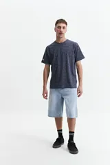 Remera verde militar con estampado de hojas en tono más oscuro, de manga corta, cuello redondo y corte regular.