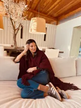 Ruana tejida color borgoña con flecos y bolsillos.