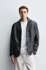 Blazer de corte relajado confeccionado en piel genuina, con cuello de solapas de muesca, manga larga y cierre frontal de tres botones. Presenta bolsillos de vivo en la cadera y un bolsillo interior.