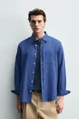 Camisa regular fit celeste confeccionada en mezcla de lino y algodón, con cuello abotonado, manga larga, bolsillo frontal en el pecho y cierre de botonadura.