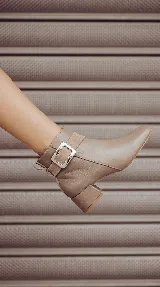 Bota corta de cuero color chocolate, con diseño minimalista, taco cuadrado de 4 cm y una hebilla metálica decorativa en el tobillo sobre una banda de gamuza.