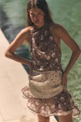 Vestido mini de cuello halter con espalda descubierta, detalle de tejido combinado con abalorios y bajo con volantes asimétricos.