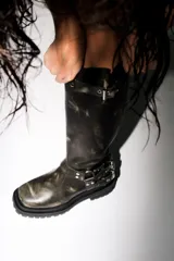 Bota alta estilo biker de cuero marrón con efecto desgastado, suela track de goma y detalles de hebillas metálicas en el tobillo y en la parte superior de la caña.