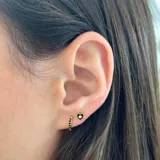Par de aros pequeños dorados de plata 925 con acabado en oro de 18k. Uno es un aro tipo argolla con circonitas negras incrustadas y el otro es un aro tipo botón con forma de corazón negro con una circonita blanca en el centro.