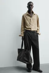 Camisa relaxed fit de algodón con elasticidad, color amarillo y gris a cuadros. Tiene cuello solapa, manga larga con puño abotonado, bajo con aberturas laterales y cierre frontal de botonadura.
