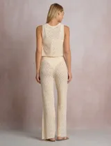 Pantalón de tiro alto con tejido calado y textura labrada, de corte recto con apertura acampanada hacia el ruedo. Cuenta con cintura elastizada y cordón de ajuste con terminaciones de caracoles decorativos.