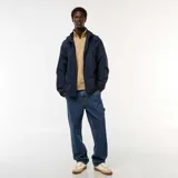 Chaqueta cortavientos azul marino con capucha, cierre frontal y bolsillos con solapa a la altura de la cintura. Presenta un diseño técnico y holgado.