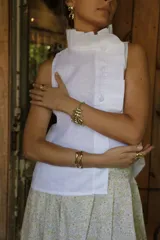 Blusa blanca de lino con volado en cuello y acceso frontal a través de cartera de botones forrados en lino.