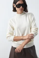 Polera de tejido de punto con cuello alto y diseño de rayas verticales sutiles. Presenta un ajuste al cuerpo y mangas largas.