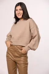 Buzo tejido de punto color beige, con cuello redondo, mangas largas con puños ajustados y diseño de corte cropped.