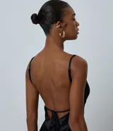 Vestido midi de satén negro con escote corazón, breteles finos ajustables y ruedo asimétrico decorado con encaje. Presenta un diseño fluido y elegante con cierre posterior.