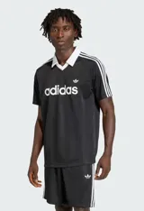 Remera polo Adidas Originals JSY negra con cuello blanco en V, tres rayas blancas en las mangas y logo Trefoil bordado. Confeccionada en tejido liviano y transpirable, con un corte regular.
