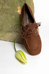 Mocasín de cuero marrón con cordones, diseño de puntera cuadrada y costuras visibles.