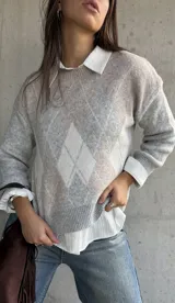 Sweater de punto con diseño de rombos en tonos gris y beige, cuello redondo, mangas largas y puños acanalados.