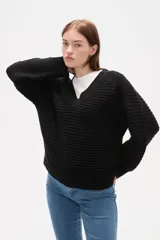 Sweater de tejido acanalado en color negro, con cuello en V y diseño holgado de manga larga.