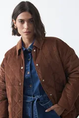 Campera capitoneada de algodón con diseño matelaseado, cuello camisero y cierre frontal con botones a presión. Presenta un corte relajado y bolsillos frontales.