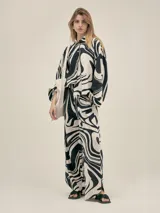 Pantalón ancho con estampado abstracto en blanco y negro, pinzas en el frente, bolsillos laterales y elástico en la cintura.