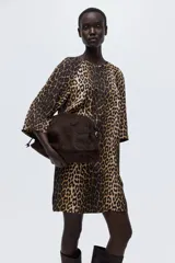 Vestido corto evasé con estampado de leopardo, escote redondo y abertura de cerradura con botón en la nuca. Mangas tres cuartos de corte raglán, pinzas en el busto y bajo recto.