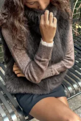 Chaleco de pelo sintético color verde oscuro, con cuello alto y sin mangas. Cierre frontal con ganchos metálicos forrados.