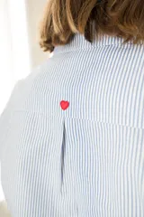 Camisa de corte clásico confeccionada en algodón con estampado de rayas verticales en azul y blanco. Presenta cuello camisero, cierre frontal con botones y mangas largas con puños abotonados.