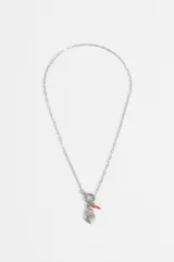 Collar de acero quirúrgico plateado con cadena de eslabones y cierre frontal T-bar. Del cierre cuelgan dijes de corazón sagrado y un pequeño amuleto rojo en forma de cuerno.
