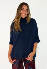 Sweater de punto color azul marino, con cuello alto y mangas cortas con puños acanalados.