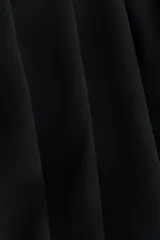 Vestido corto negro de diseño cruzado con escote en V profundo y frente drapeado. Presenta hombreras, mangas largas y una silueta ceñida al cuerpo con frunces laterales.