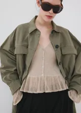 Cardigan de punto fino color beige, entallado, con cuello en V, manga larga acampanada, bajo con volante y cierre frontal con botones.